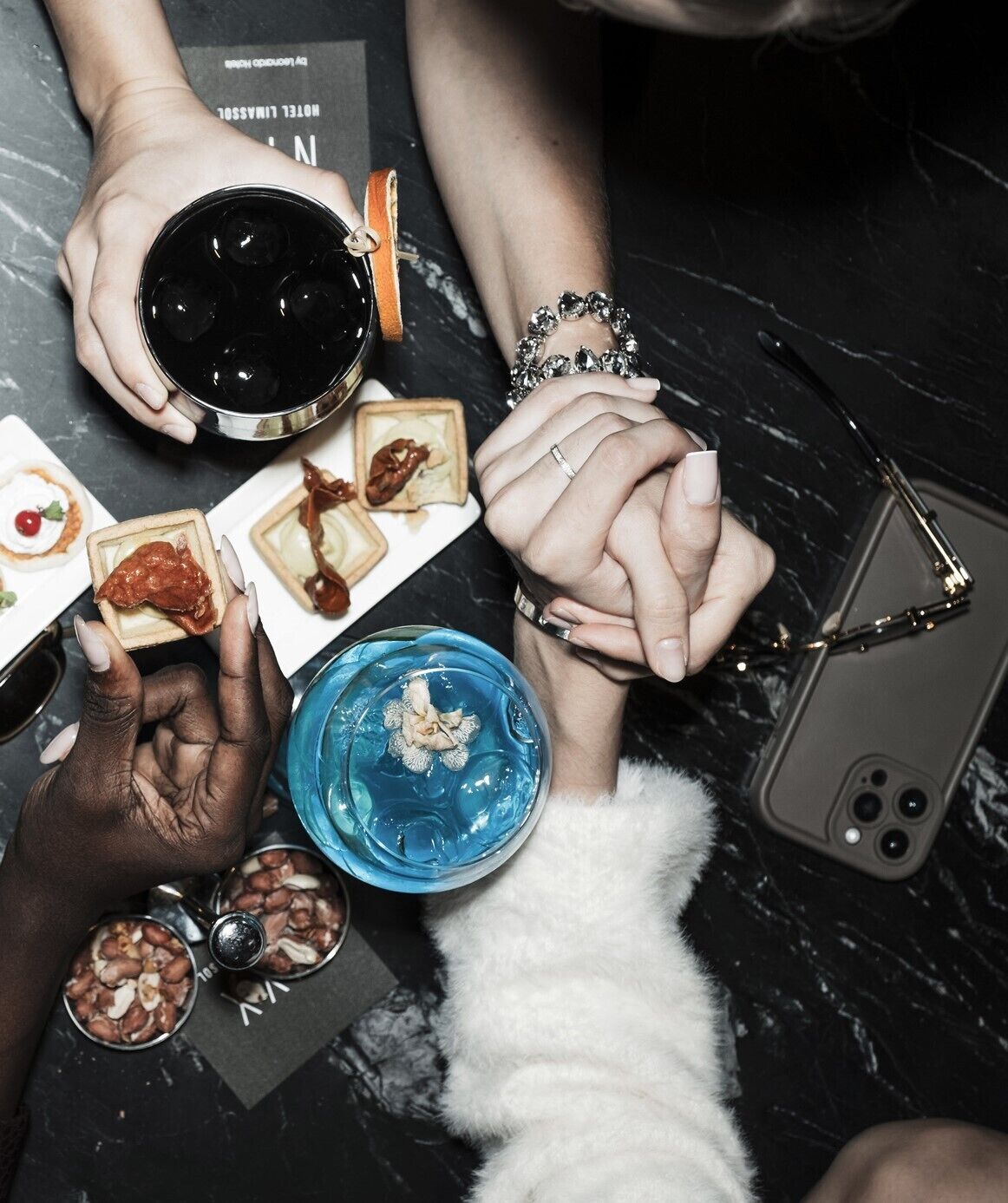 A group of people holding hands around a table with various food items and drinks.