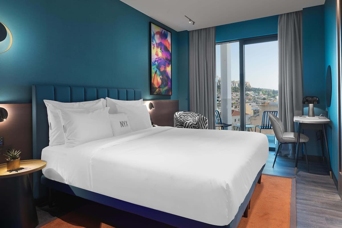 Ein modernes Hotelzimmer mit einem großen Bett, einem Schreibtisch und Blick auf die Stadt.