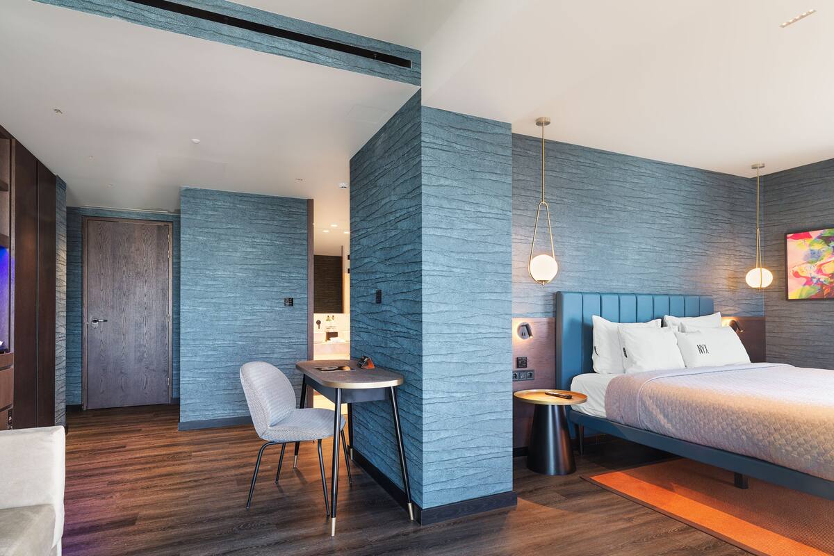 Ein modernes Schlafzimmer mit einem Bett, Nachttischen und einem Schreibtisch mit Stuhl.