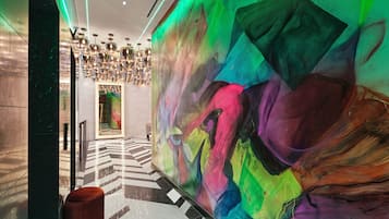 A modern lobby with a large abstract mural, a patterned floor, and a chandelier.
