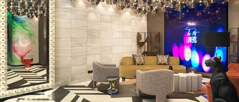 A modern lounge area with a reflective ceiling, a large mirror, and a neon sign.