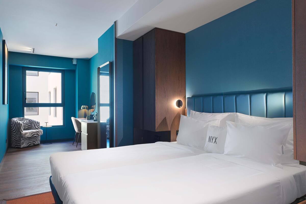 Ein modernes Hotelzimmer mit einem großen Bett, einem Schreibtisch und einem Stuhl.