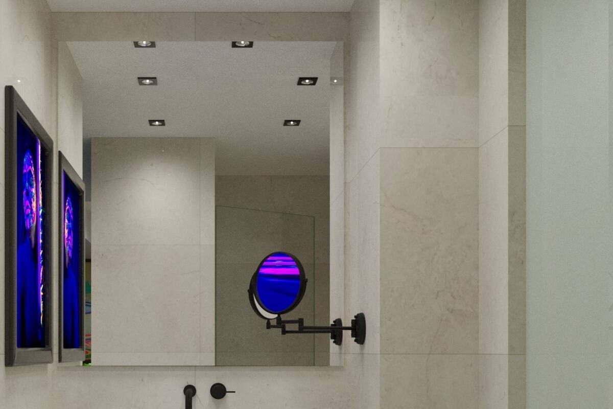 Ein modernes Badezimmer mit einem weißen Waschbecken, zwei Seifenflaschen, einem Spiegel und einem blauen Dekoelement an der Wand.