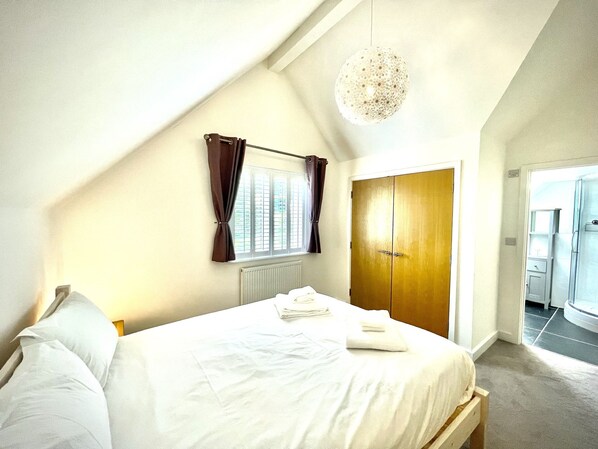 A bedroom with a bed, a wooden wardrobe, a radiator, and a window with curtains.