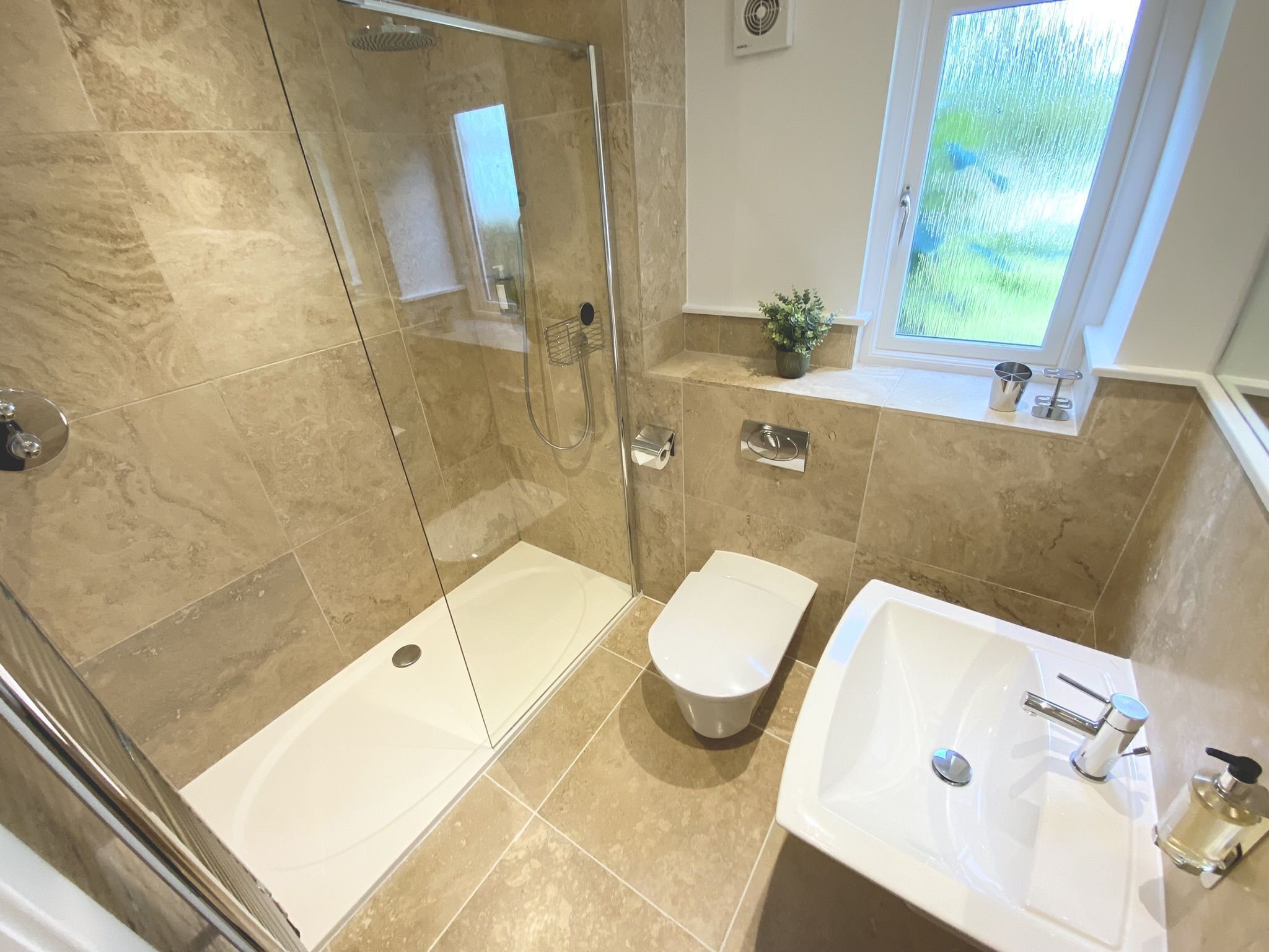 A bathroom with a glass-enclosed shower, a bidet, and a sink with a mirror.