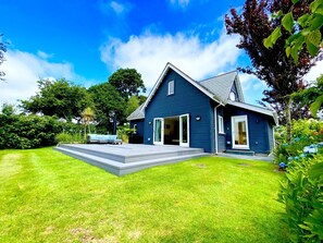 A modern two-story house with a large front yard, a covered patio, and a garage. - Luxury 4 bed detached villa, minimum 3 bathrooms, large open plan lounge/kitchen/dining area. (St Austell)
