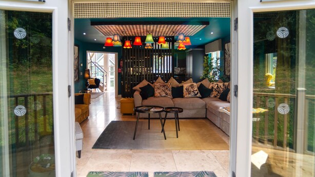Un salon moderne avec un canapé, deux tables basses et des lampes suspendues aux couleurs vives.
