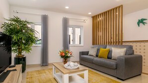 Una sala moderna con un sofá gris, una mesa de centro de madera y una planta verde grande.