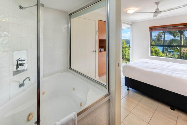 A modern bathroom with a glass-enclosed shower, a bathtub, and a large mirror.