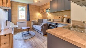 A compact kitchen with wooden cabinetry, a built-in stove, and a sink. - Chalet atmosphere for 4 - 80m from the slopes (Genos)