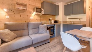 A compact living space with a sofa, a dining table, and a kitchenette. - Chalet atmosphere for 4 - 80m from the slopes (Genos)