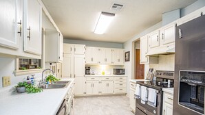 A modern kitchen with white cabinets, stainless steel appliances, and a central island with a sink and a coffee maker.