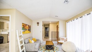 A living room with a sofa, a coffee table, a chair, and a painting on the wall.