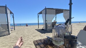 A beach scene with a wooden table, a glass of water, and a metal bucket. - ALL COMFORT, SUPERB VIEW, large TERRACE Los Flamingos Ideal families (Estepona)
