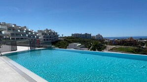 A clear blue pool with a view of modern buildings and a distant coastline. - ALL COMFORT, SUPERB VIEW, large TERRACE Los Flamingos Ideal families (Estepona)