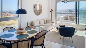 A modern living room with a large window, a round dining table, and a sofa. - ALL COMFORT, SUPERB VIEW, large TERRACE Los Flamingos Ideal families (Estepona)