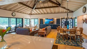 Un vaste espace de vie comprenant une grande table à manger, des sièges confortables et une cuisine équipée d’appareils électroménagers modernes.