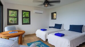 Une chambre avec deux lits, une petite table et un ventilateur de plafond.