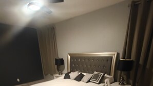 A bedroom with a large bed, two bedside tables with lamps, and a ceiling light. - Lovely white & Grey home (Buckeye)