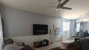A modern living room with two brown sofas, a flat-screen TV, a ceiling fan, and a white cabinet. - Lovely white & Grey home (Buckeye)