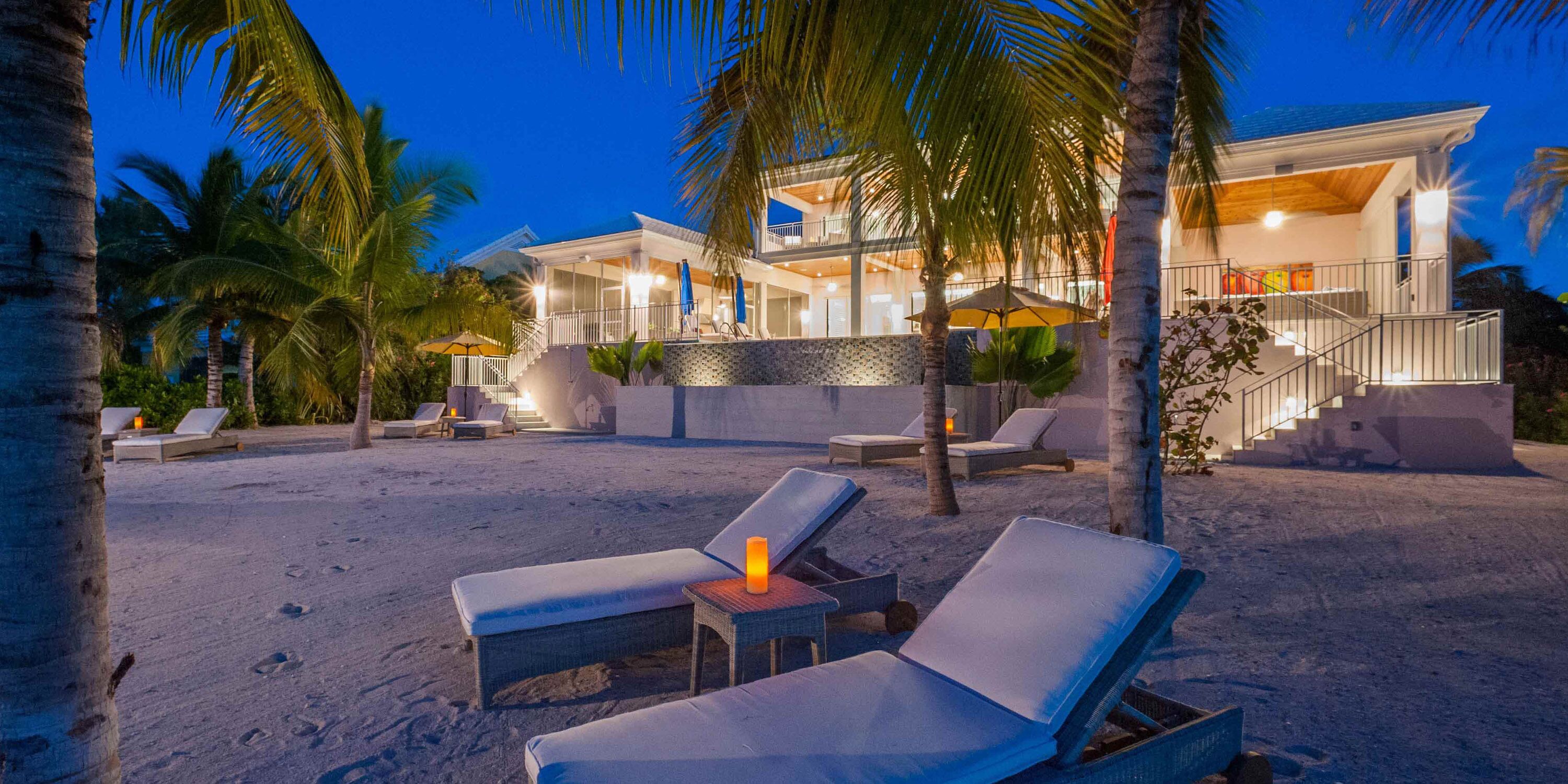 Ein Strandgrundstück mit Pool, Liegestühlen und einer Treppe zu einem überdachten Bereich.