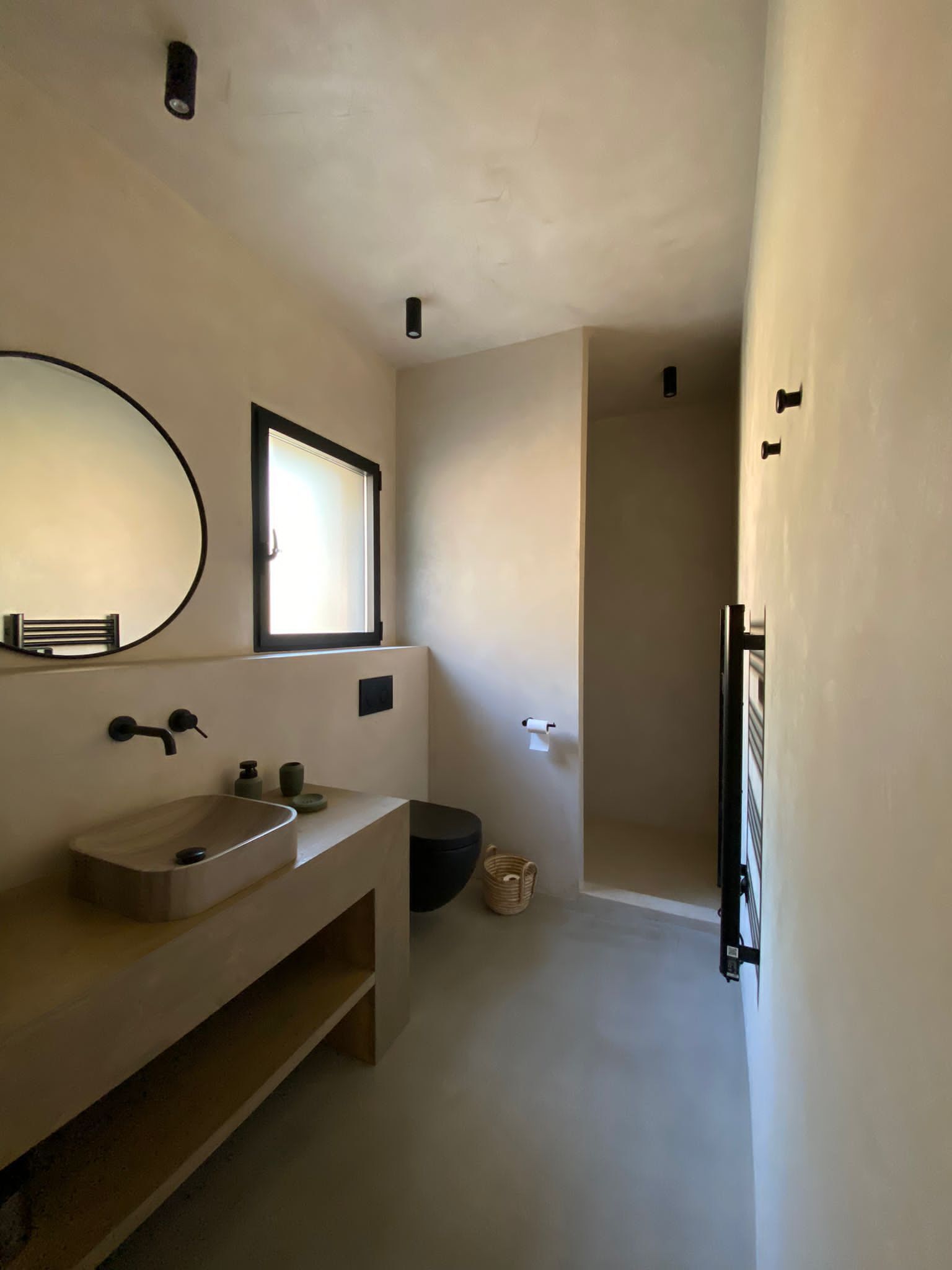 Un baño moderno con un espejo grande, un lavamanos y una ventana.