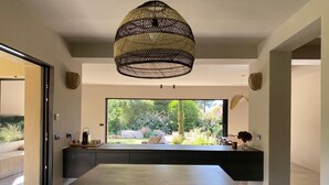 Een moderne keuken met een groot raam, een eethoek en een hanglamp.