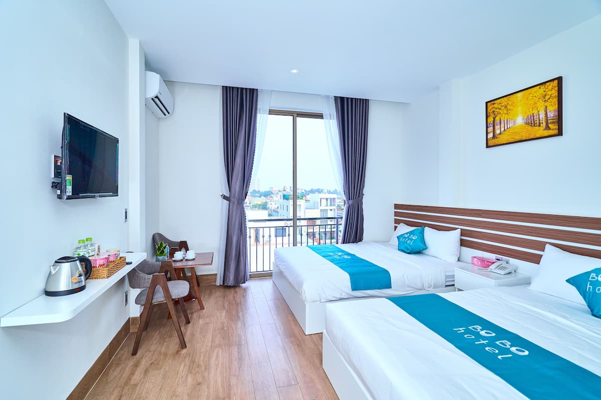 Ein Hotelzimmer mit zwei Betten, einem Fernseher, einem Balkon und Blick auf die Stadt.