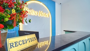 A hotel reception desk with a neon sign reading "Bo Hotel" and a reception sign. - BOBO Boutique Hotel (Ho Chi Minh City)