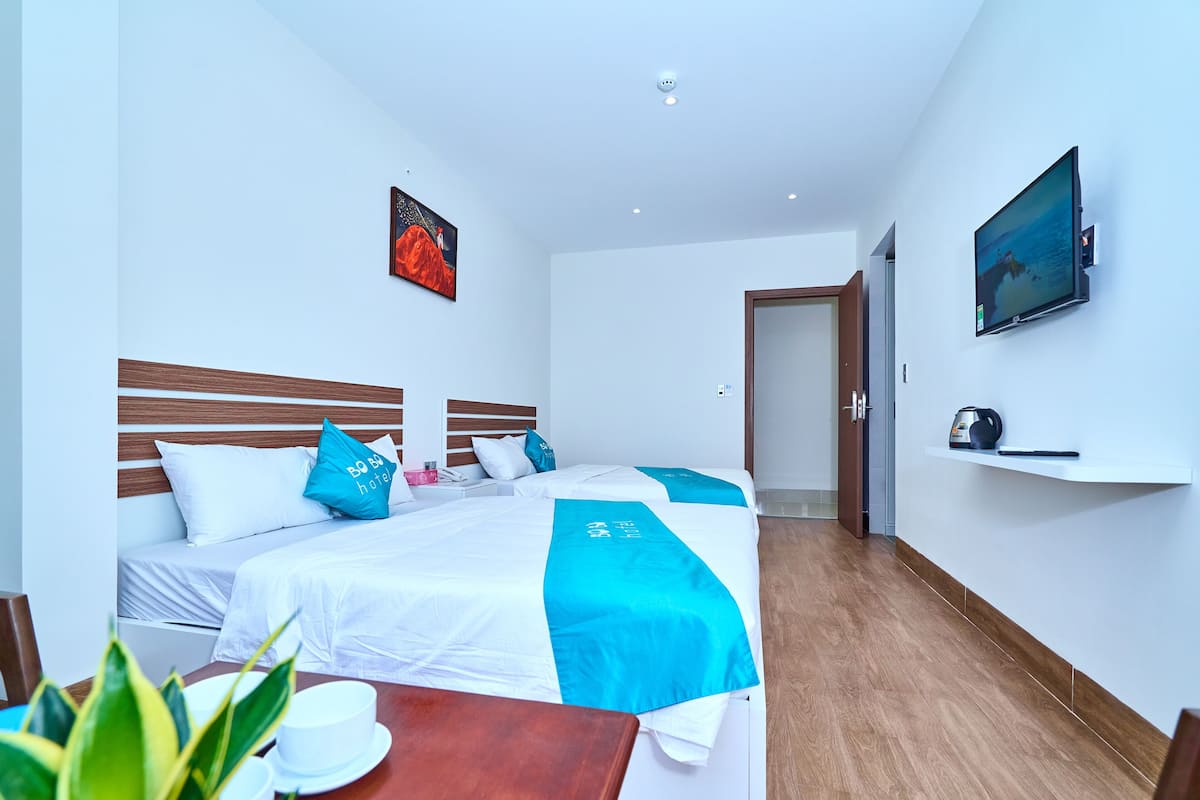 Ein Hotelzimmer mit einem Bett, einem an der Wand montierten Fernseher und einem kleinen Tisch mit Tasse und Untertasse.