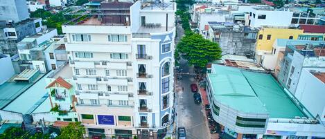 Un edificio de varios pisos con terraza en la azotea, un letrero visible que dice 'Doro Hotel', y vista de la calle con coches estacionados y edificios.