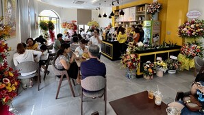 A restaurant with indoor seating, a counter with a menu, and decorative flowers. - BOBO Boutique Hotel (Ho Chi Minh City)