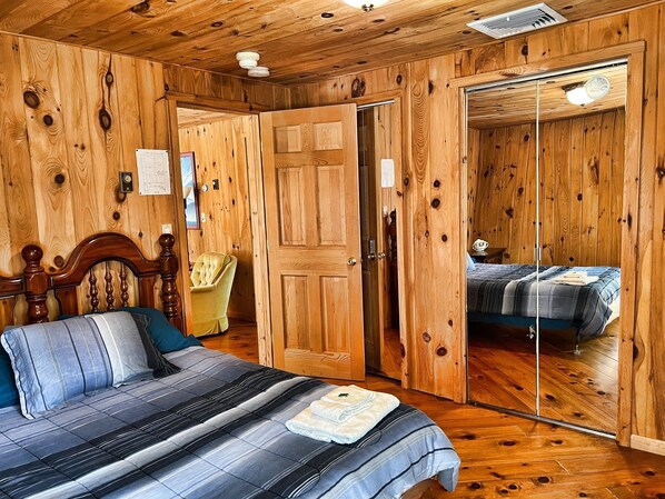 Un dormitorio con paneles de madera, una cama, una silla y un armario.