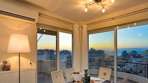 Ein Essbereich mit Tisch für vier Personen, große Fenster mit Blick auf die Stadt und ein Heizkörper links.