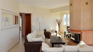Ein geräumiges Wohnzimmer mit Kamin, einer Sofagarnitur und einem Fernseher.