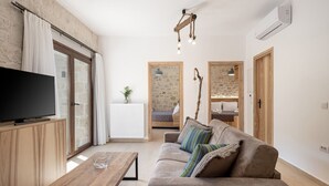 Un salon moderne doté d’un téléviseur à écran plat, de meubles en bois, d’un canapé avec des coussins à rayures et d’un luminaire suspendu.