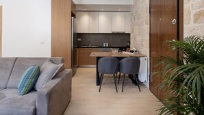 Une cuisine moderne avec des meubles de rangement en bois, une table à manger avec des chaises et une grande porte en bois.