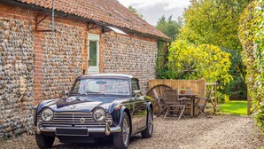 A vintage car parked in front of a stone building with a tiled roof. - The Stables, Edingthorpe, Norfolk (North Walsham)