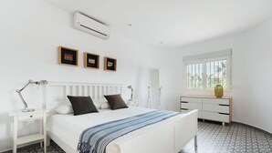 A bedroom with a bed, bedside tables, a dresser, a window, and wall-mounted artwork. - Villa MONTE CRISTO by Abahana Villas (Teulada)