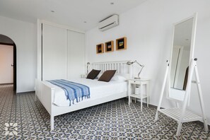 Une chambre à coucher comprenant un lit, une table de chevet, une lampe, un miroir et des carreaux de sol à motifs.