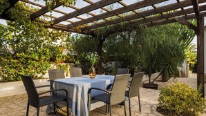 An outdoor patio with a table and chairs, surrounded by greenery and a pergola structure. - Villa MONTE CRISTO by Abahana Villas (Teulada)