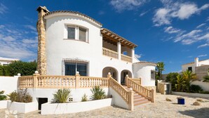 A two-story building with a white facade, a stone column, a wooden staircase, and a balcony. - Villa MONTE CRISTO by Abahana Villas (Teulada)