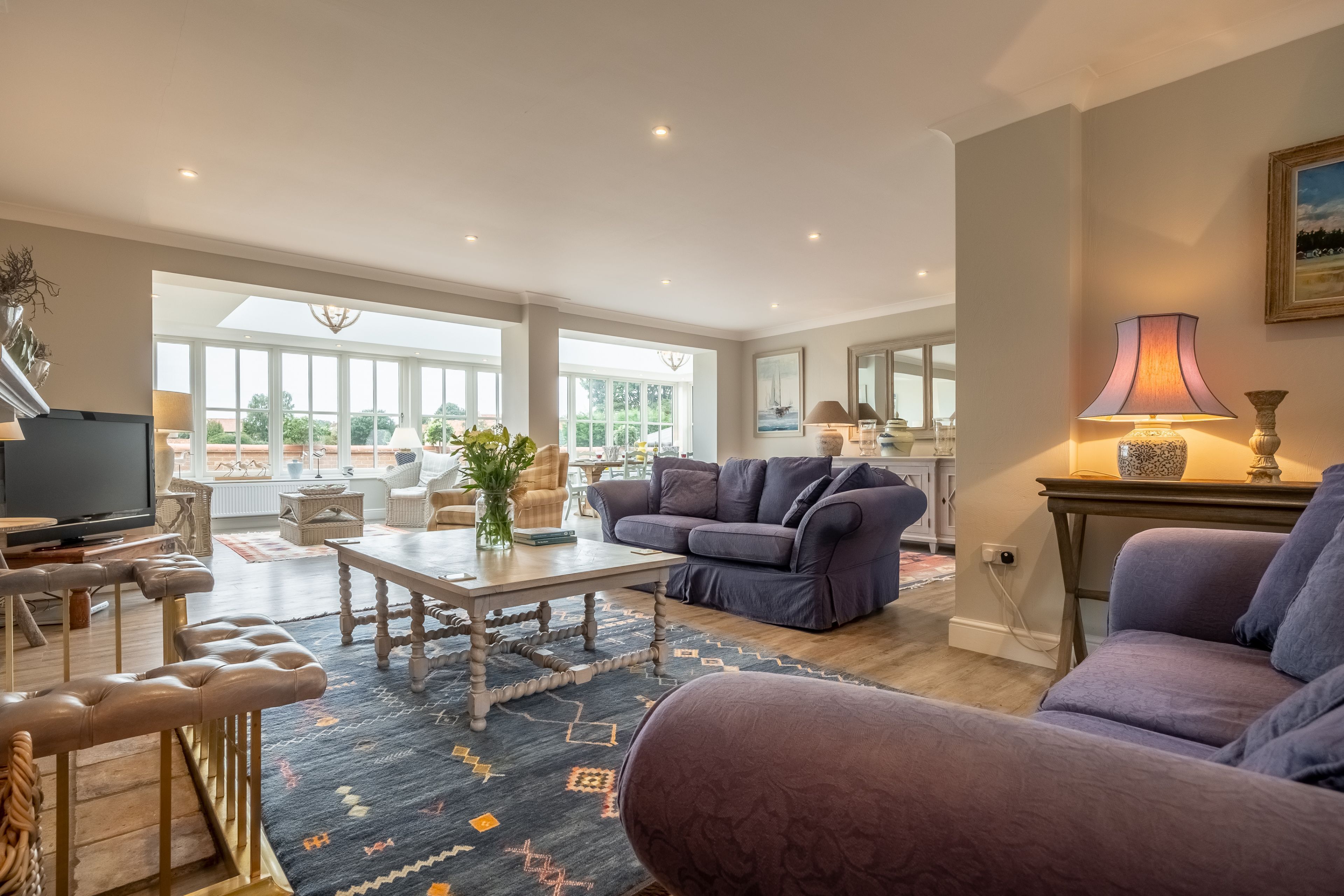 A spacious living room with a large window, a sofa, a coffee table, and a TV.