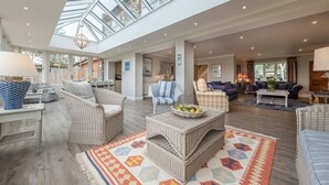 A spacious living area with wicker furniture, a glass ceiling, and a view of the outside. - Field Piece Cottage, Burnham Market, Norfolk (Burnham Market)