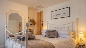 Une chambre à coucher avec un lit à baldaquin blanc, une porte en bois, un tableau encadré au mur et une table de chevet avec une lampe.