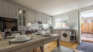 Une cuisine moderne avec des meubles blancs, un four encastré et un lave-linge.