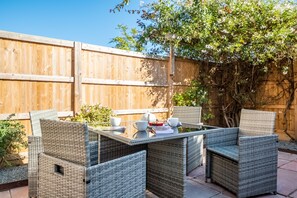 Un patio con mobiliario de mimbre y una valla de madera.