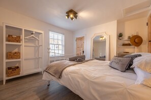 Un dormitorio con una cama grande, un armario con cestas, un espejo y una lámpara en el techo.