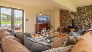Una sala de estar moderna con una mesa de centro de vidrio, asientos cómodos, una chimenea y un amplio ventanal con vistas al exterior.