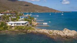 Une propriété située sur la côte, comprenant plusieurs bâtiments, un quai et des bateaux amarrés dans l’eau.